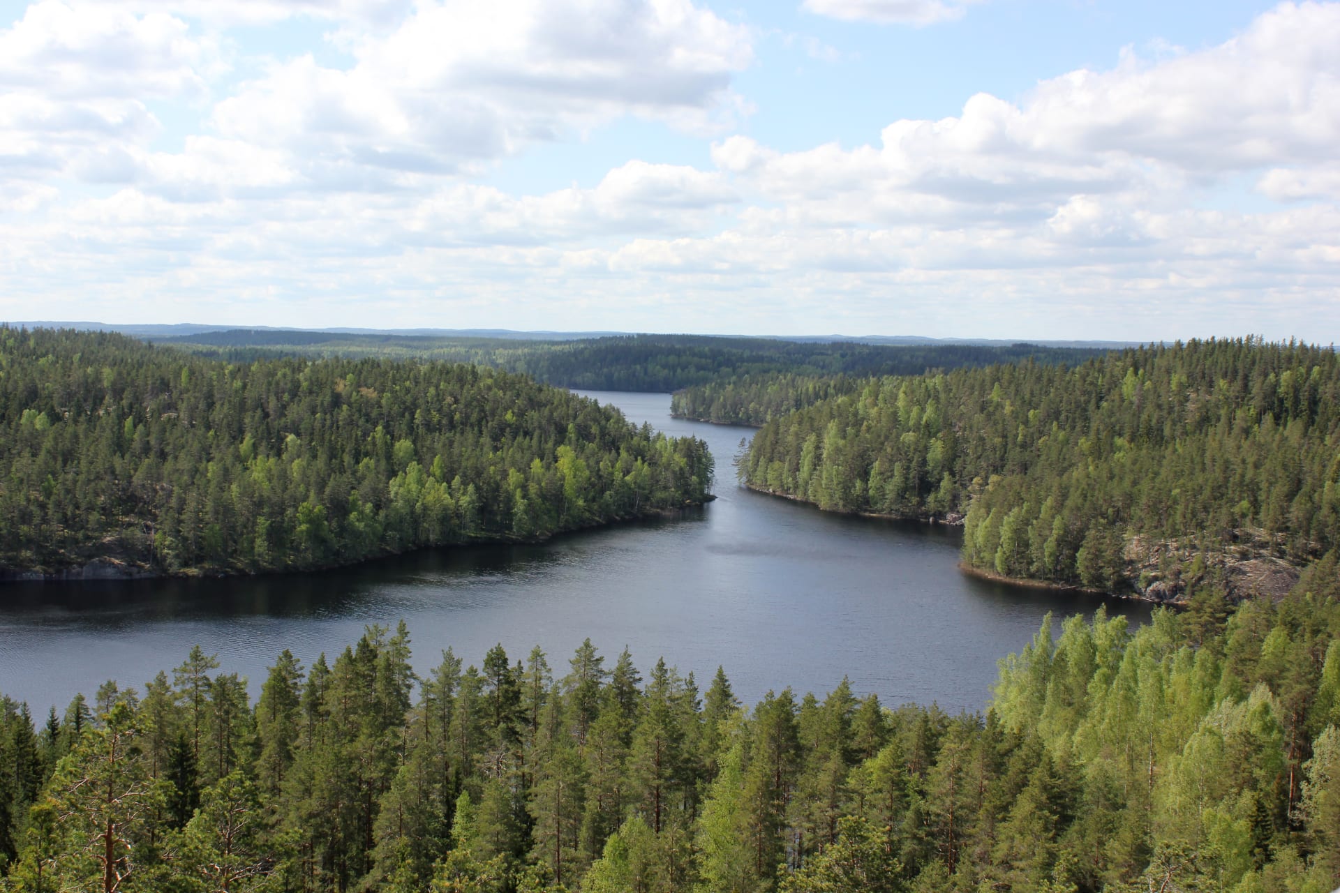 Maisemakuvan etualalla on tyyni lampi. Se takana kohoaa jyrkkä kallionseinämä, jonka laella kasvaa metsää. Sää on hieman harmaa ja syksyinen ja ilmassa on utua. Kuva: Mari Laukkanen