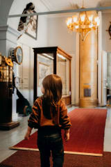 A small boy is watching at the museum objects in the museumu0026#039;s entrance hall.