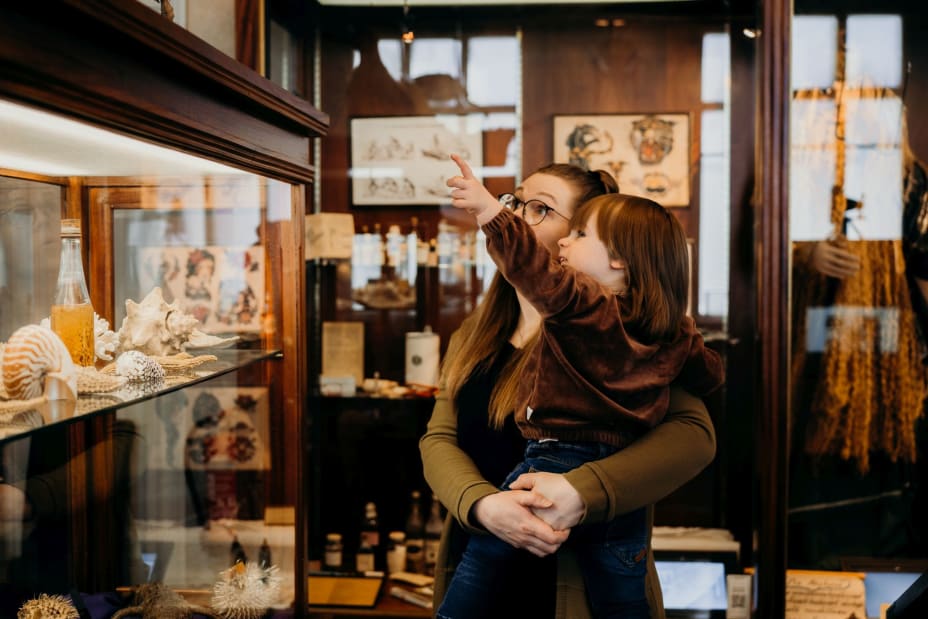 A woman with a small boy in his lap is watching the museum objects.