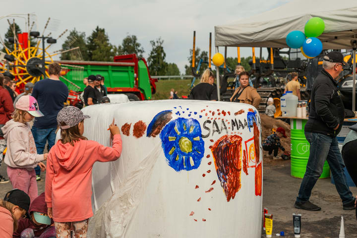 Lapsi maalaamassa heinäpaalia.