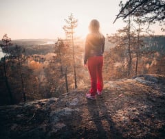 Nainen ihailee Neitvuorelta Saimaa-näkymää ilta-auringossa. The view from Neitvuori mountain in the evening sun.