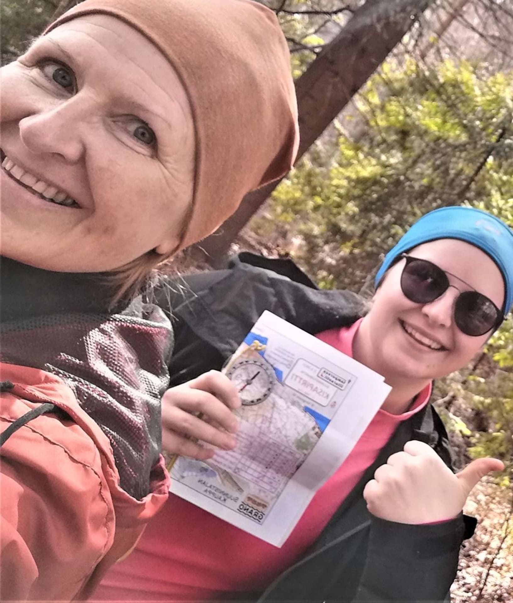 Kaksi naista hymyilee, toisella kartta ja kompassi kädessä