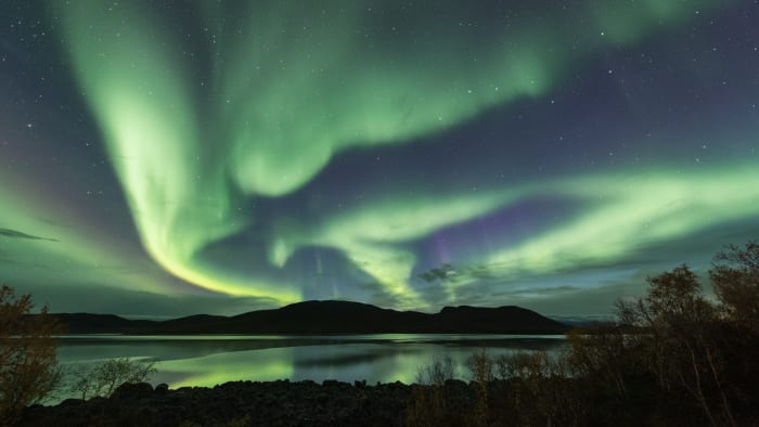 Northern lights above a lake with reflections