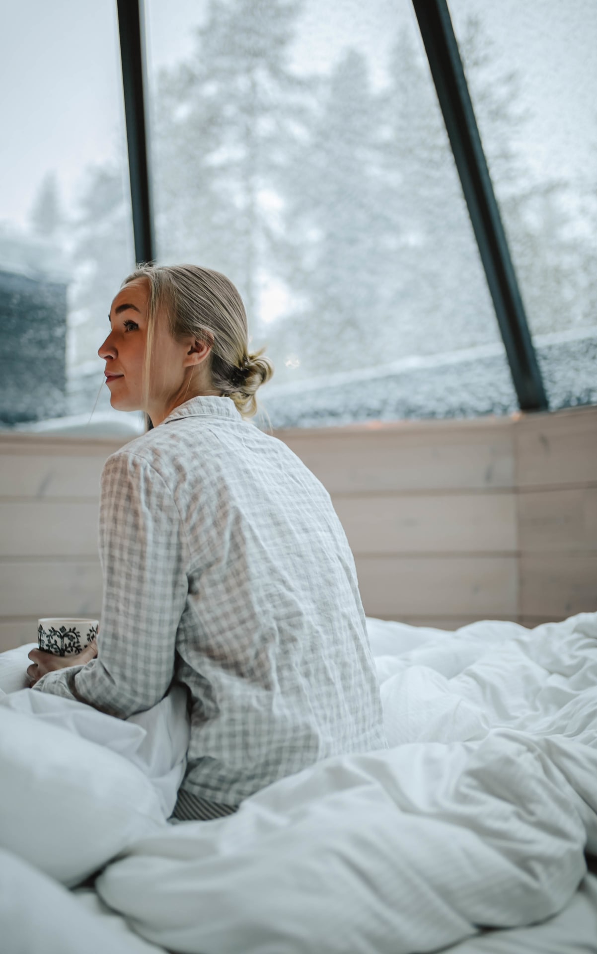 Morning in bed, woman waking up, first snow outside the window