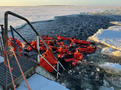 people swimming with survival suits in the frozen sea water