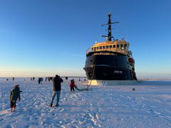 icebreaker arktis stopped in the middle of the frozen sea and people walking on sea ice