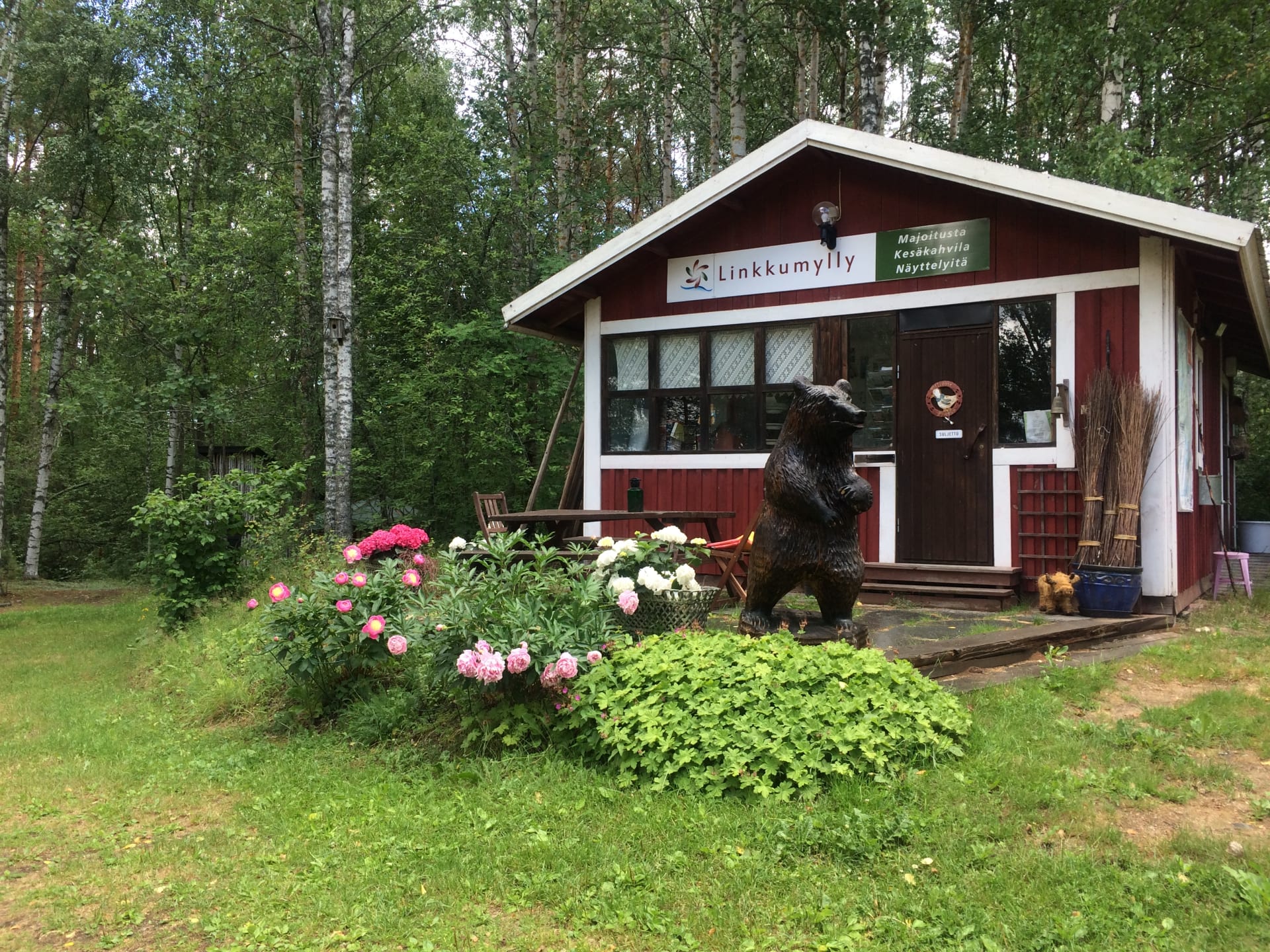 Summer cafe exterior. Punainen kesäkahvila, jonka edessä on pionipenkki. 