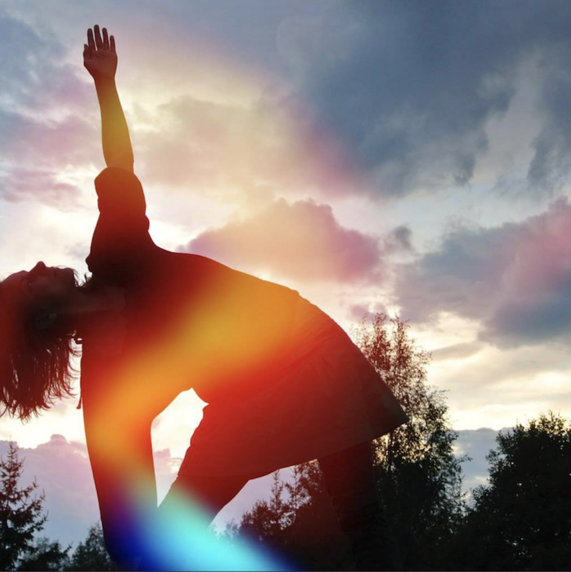 Nainen joogaa trikonasanassa taustalla illan sinitaivas. Woman doing yoga trikonasana framed by evening sky.