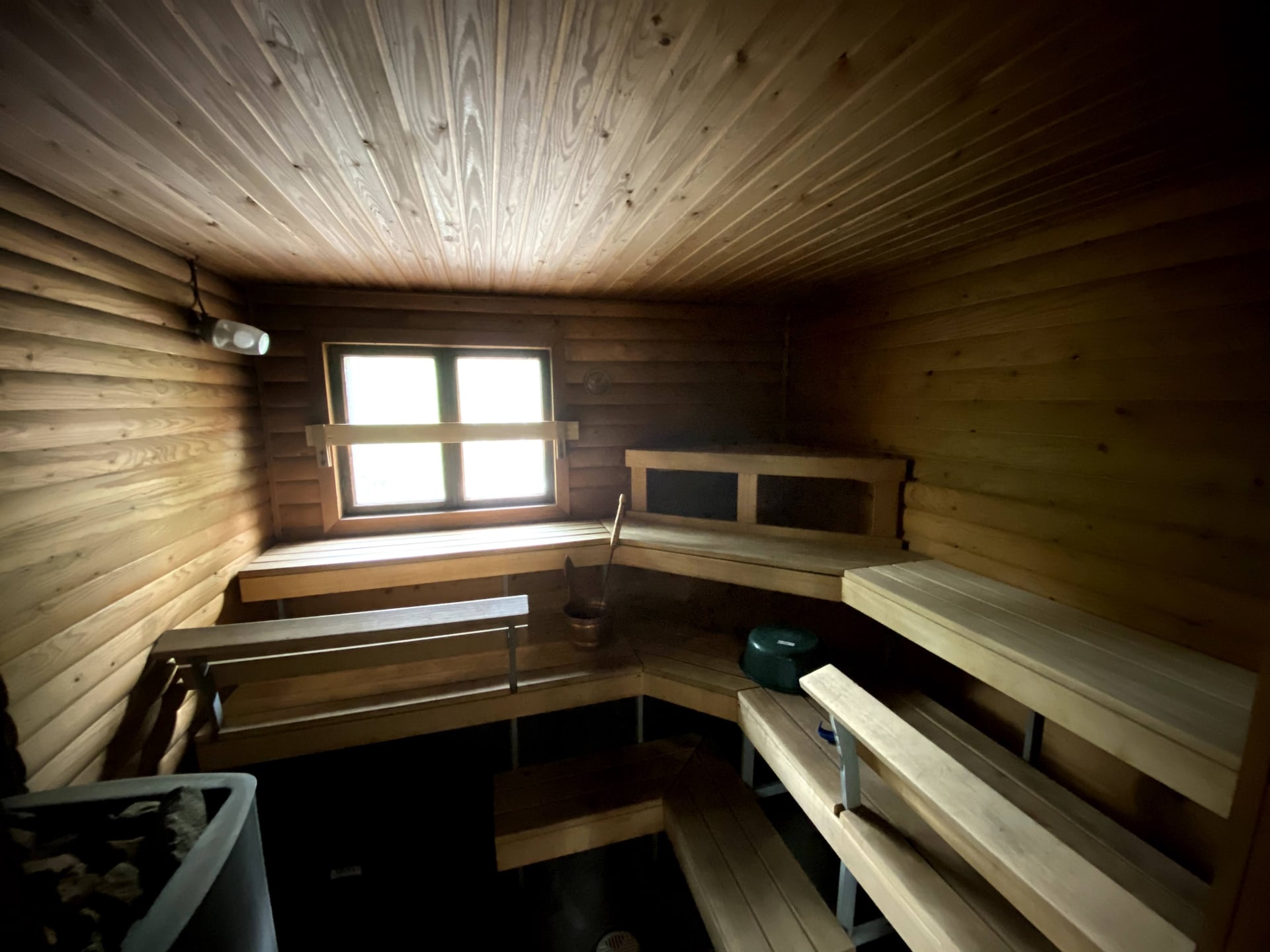Interior of a wooden sauna with tiered benches and a window letting in soft natural light.