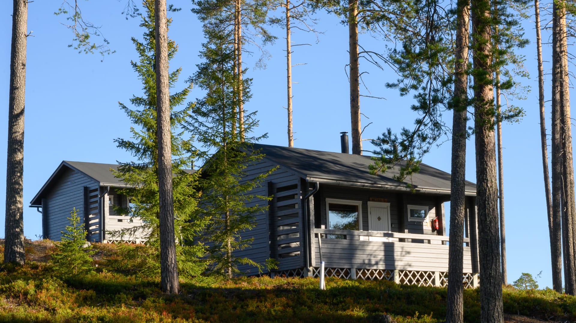 Hirsimökit rinteessä järven rannalla.