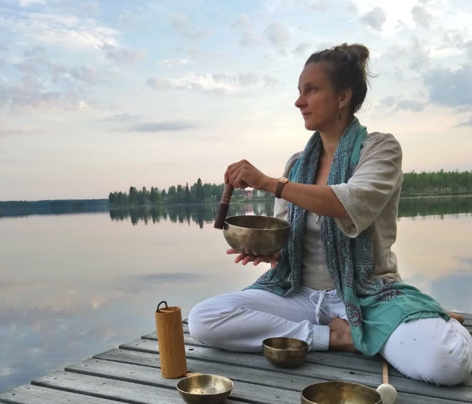 Nainen soittaa äänimaljoja laiturilla.