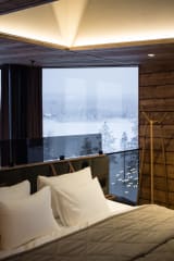 A built-in coffee station inside a Jänkä villa featuring a coffee machine, glassware, and warm lighting within a wooden interior.