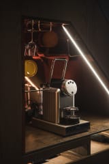 A modern villa kitchen at Jänkä with dark wood cabinets, a stone countertop, dining table, and large windows letting in natural winter light.