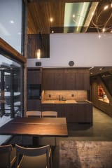 A villa bathroom at Jänkä with dark stone surfaces, double sinks, warm lighting, and a modern sauna stove visible through glass.
