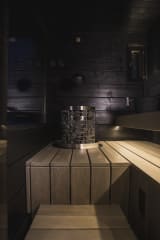 A modern Jänkä villa surrounded by snow-covered trees, glowing warmly from inside during winter twilight.