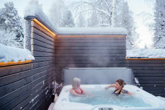 Two people in a heated outdoor jacuzzi in Apukka Resort.