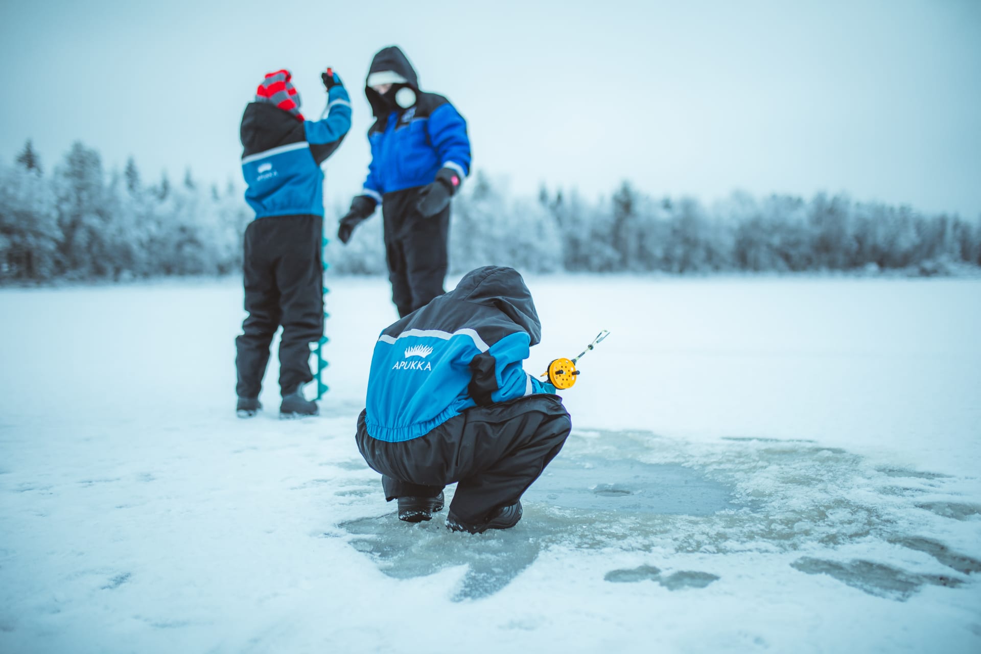 A family ice-fishing on the wilderness lake by Apukka Resort.