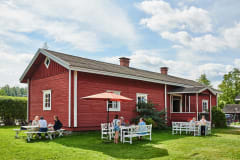 Kesäkuva museoalueesta ja ulkona on pöytiä, joissa voi istua kahvilla.