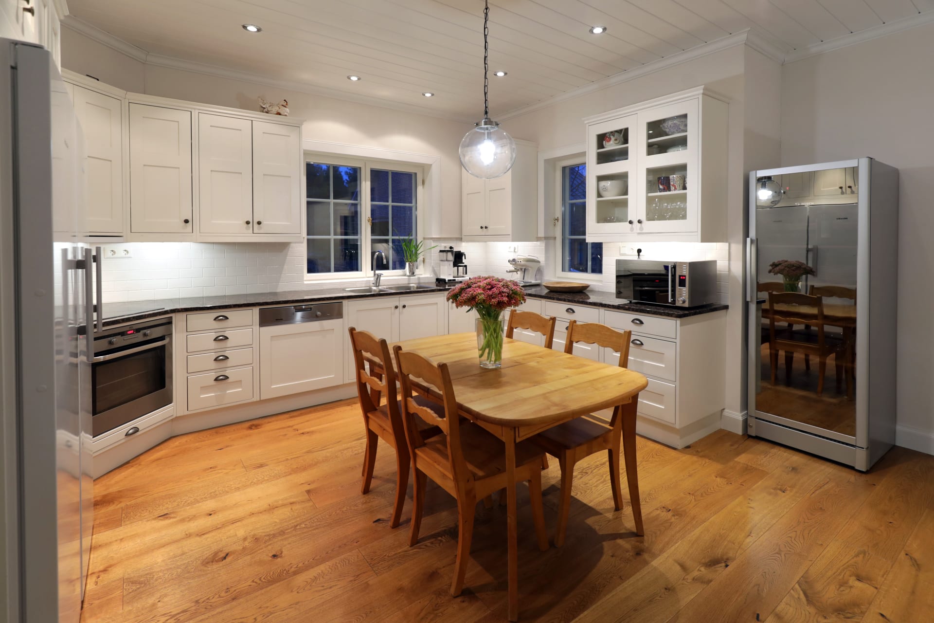 Fully equipped Villa Cone Beach kitchen featuring an induction cooktop, energy-saving appliances, a granite countertop, and a secondary dining table.