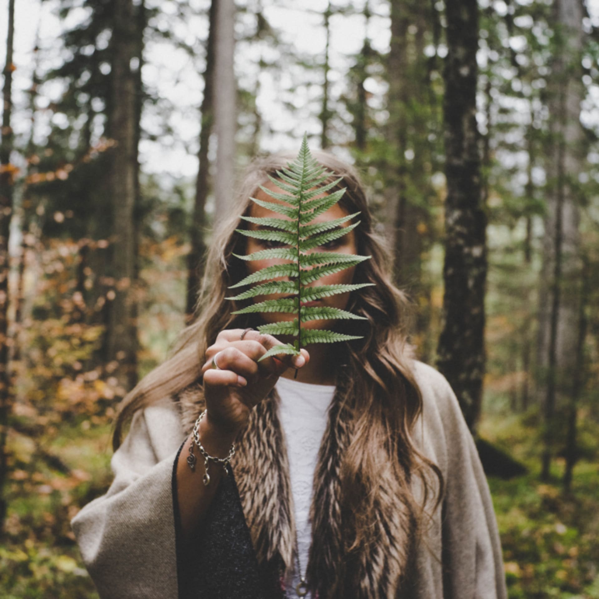 Girl holdind a plant in Finnish forrest.