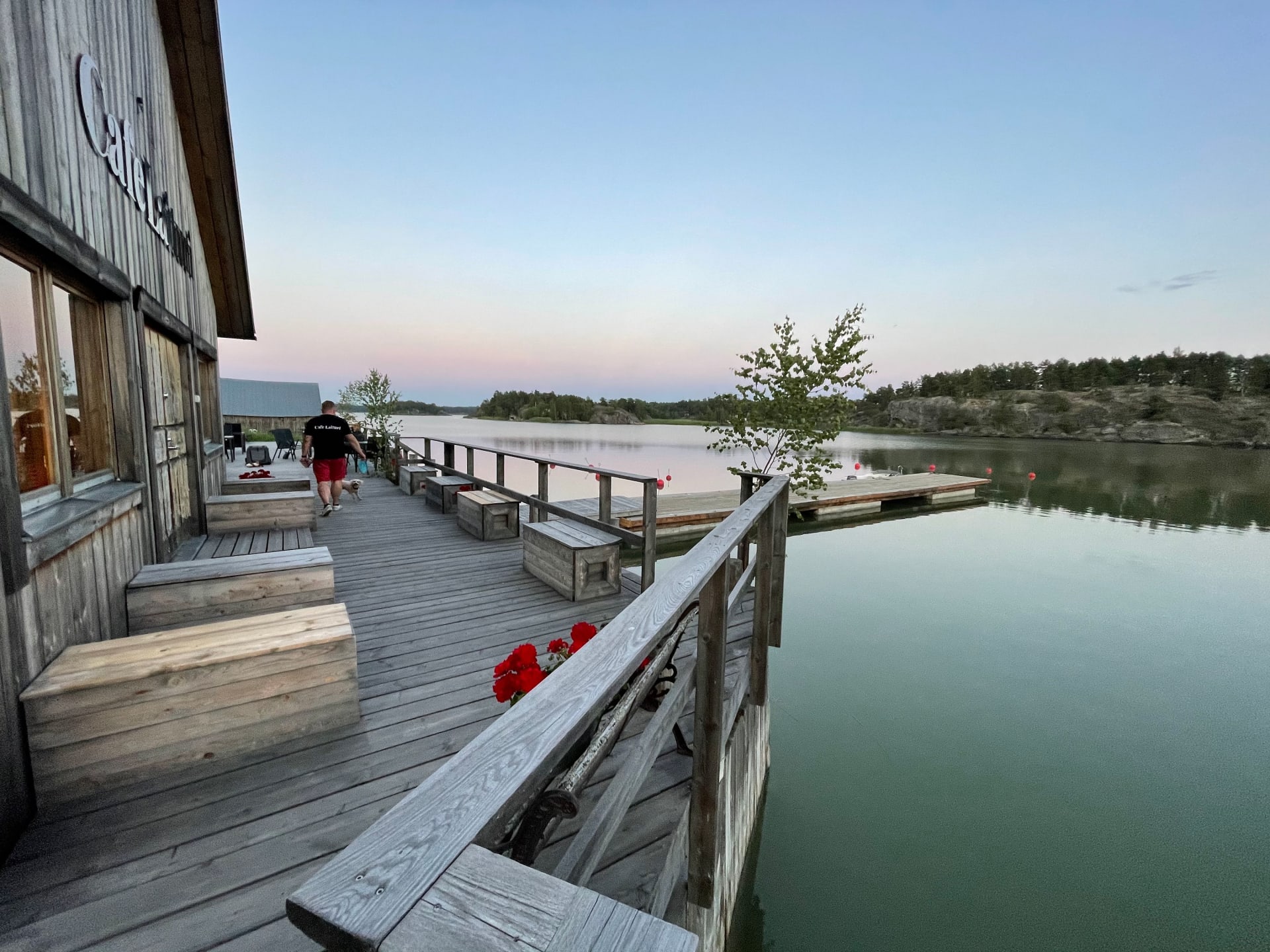 The tranquil evening at Cafe Laituri, with its rustic wooden deck stretching along the serene water, invites a peaceful walk or a moment to soak in the twilight serenity.