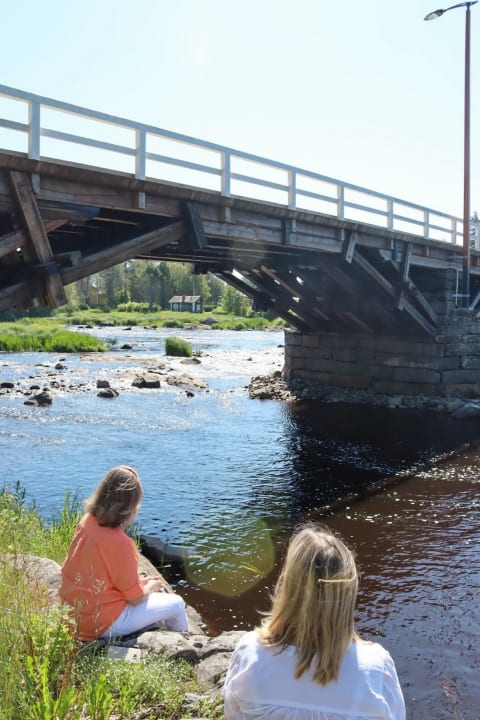 Two women on the bank of the river Pyhäjoki by historical Isosilta bridge 