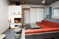 A couch, table and fireplace with fire.