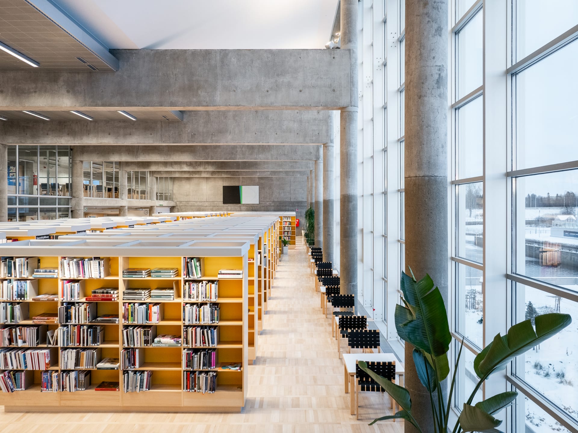 Korkea sisätila, vasemmalla kirjahyllyjä, oikealla korkea ikkunaseinä.