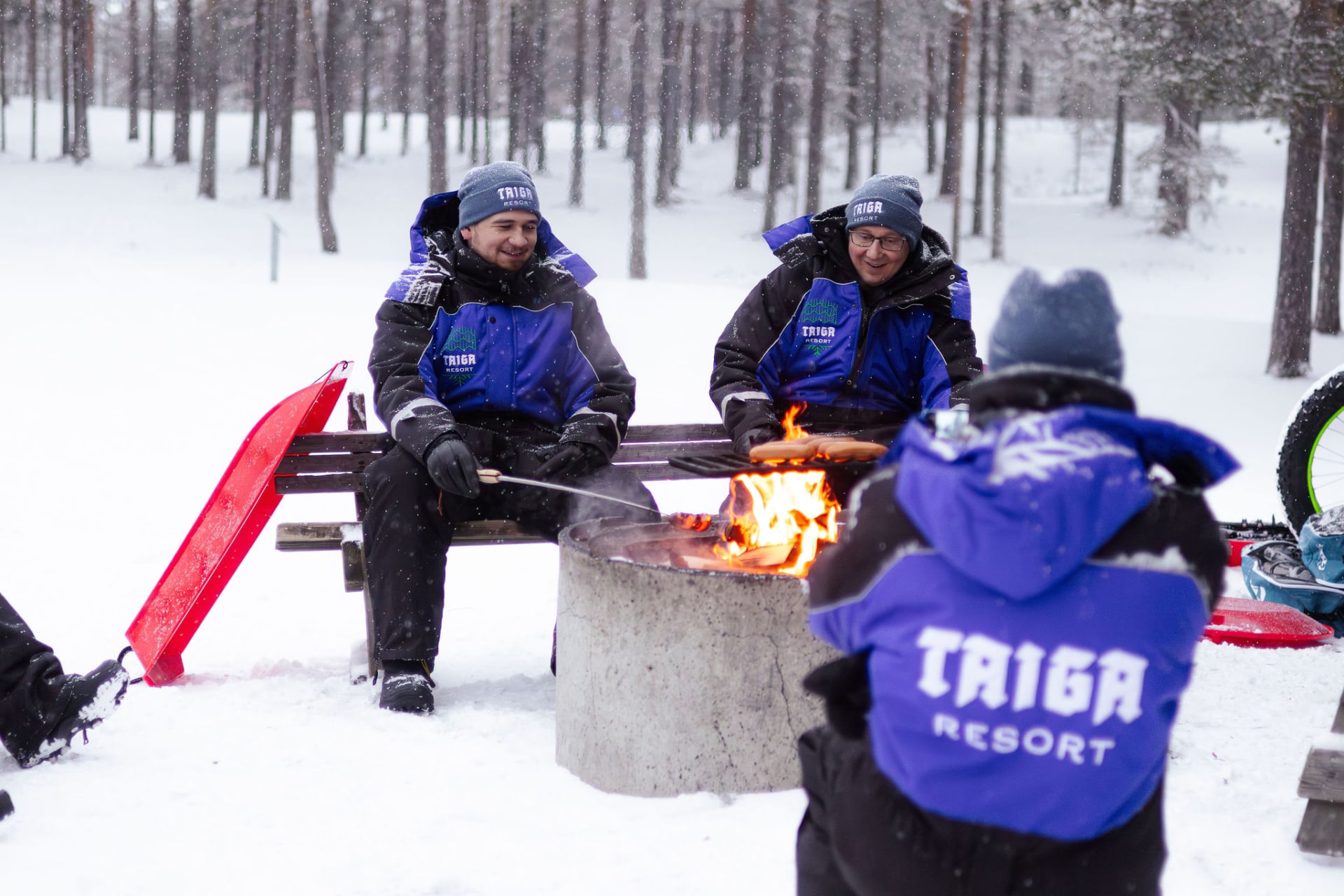 Men grilling sausages outdoors in winter