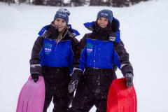 women having fun sledding in winter time