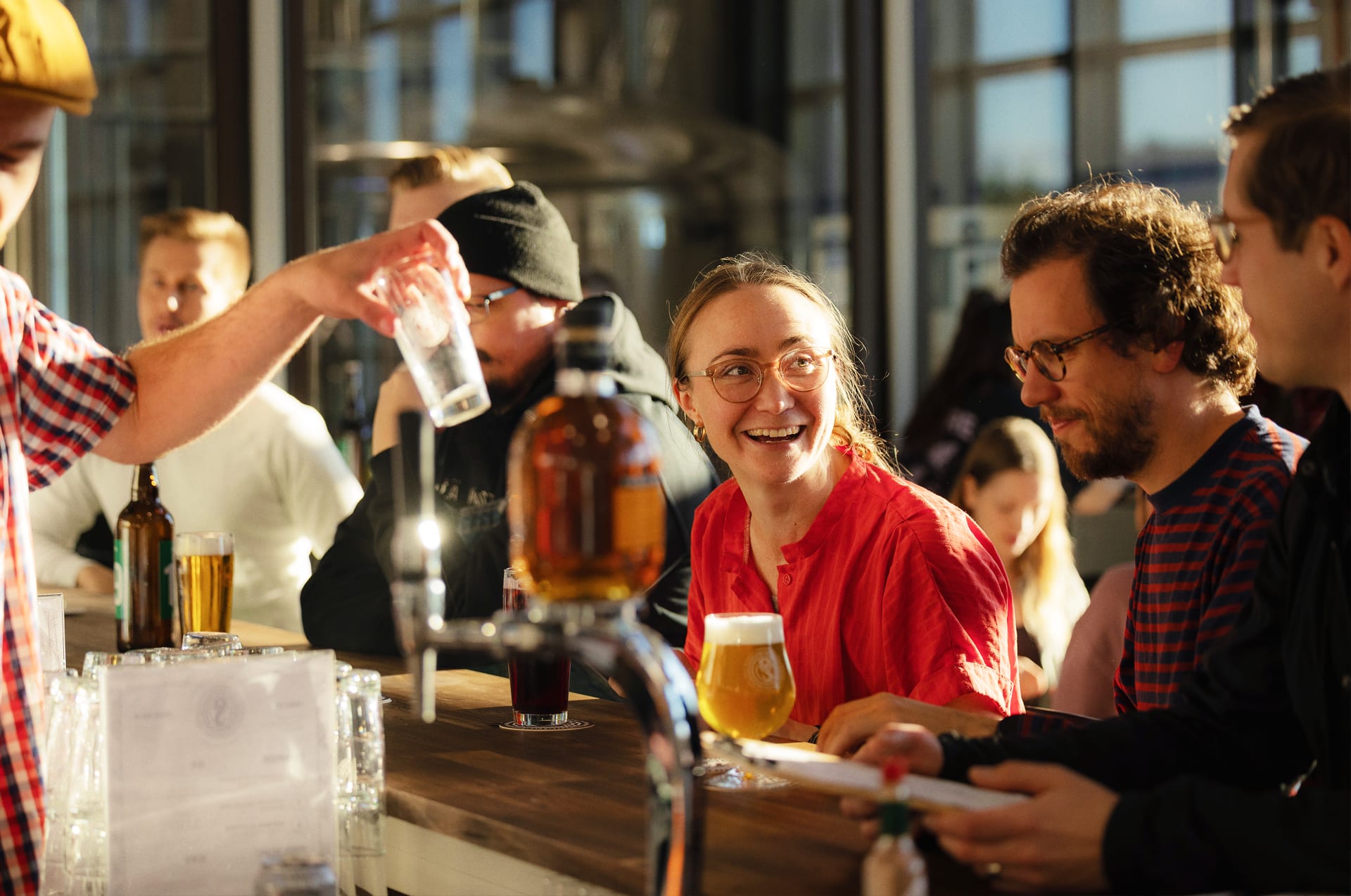 Happy customers enjoying drinks at the wooden bar counter of Varikko Taproom