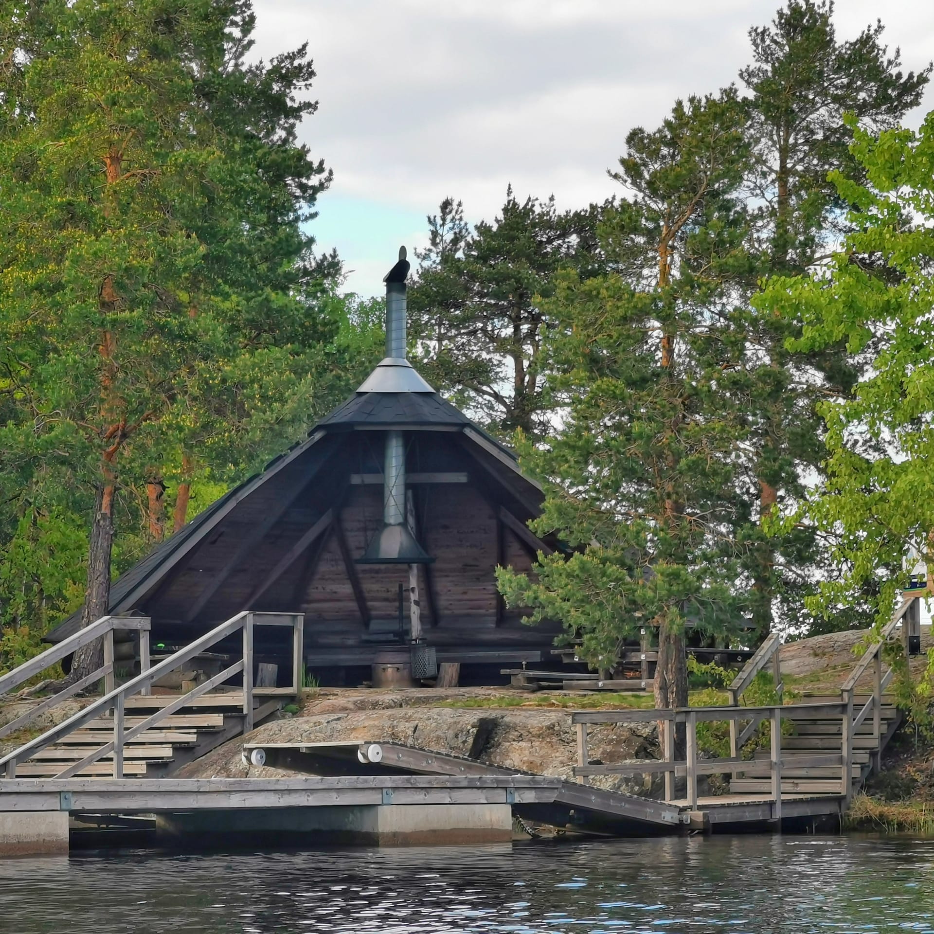 Laavu, jolle johtaa puiset portaat laiturilta. Metsää kesällä