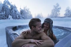 Couple enjoying outdoor jacuzzi at Arctic SnowHotel & Glass Igloos.