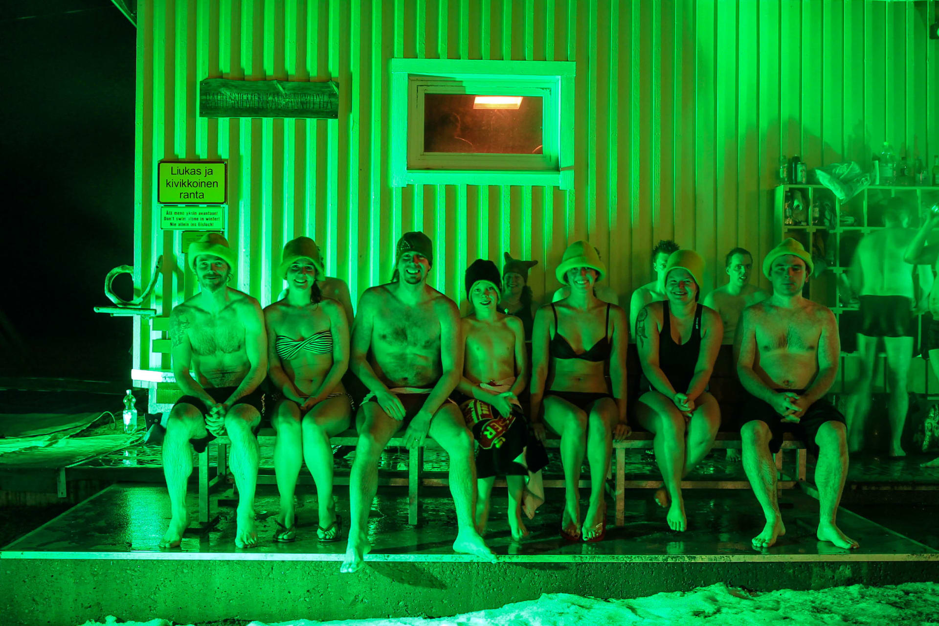 Saunojat vilvoittelevat ulkona tunnelmallisessa, vihreässä valossa kylki-kyljessä.