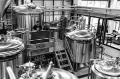 Dramatic black and white photograph of modern brewing equipment and fermentation tanks