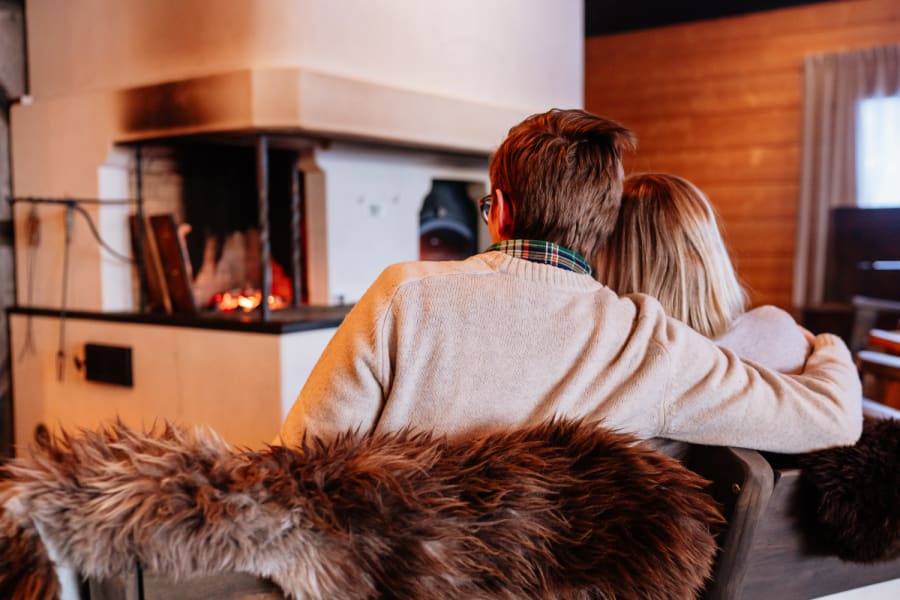 A couple by the massive fireplace of Aitta Restaurant in Apukka Resort Rovaniemi Lapland Finland