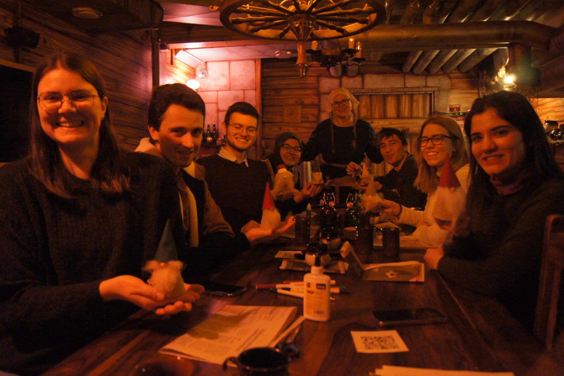 people posing with their newly-made tonttu figurines at a fantasy tavern