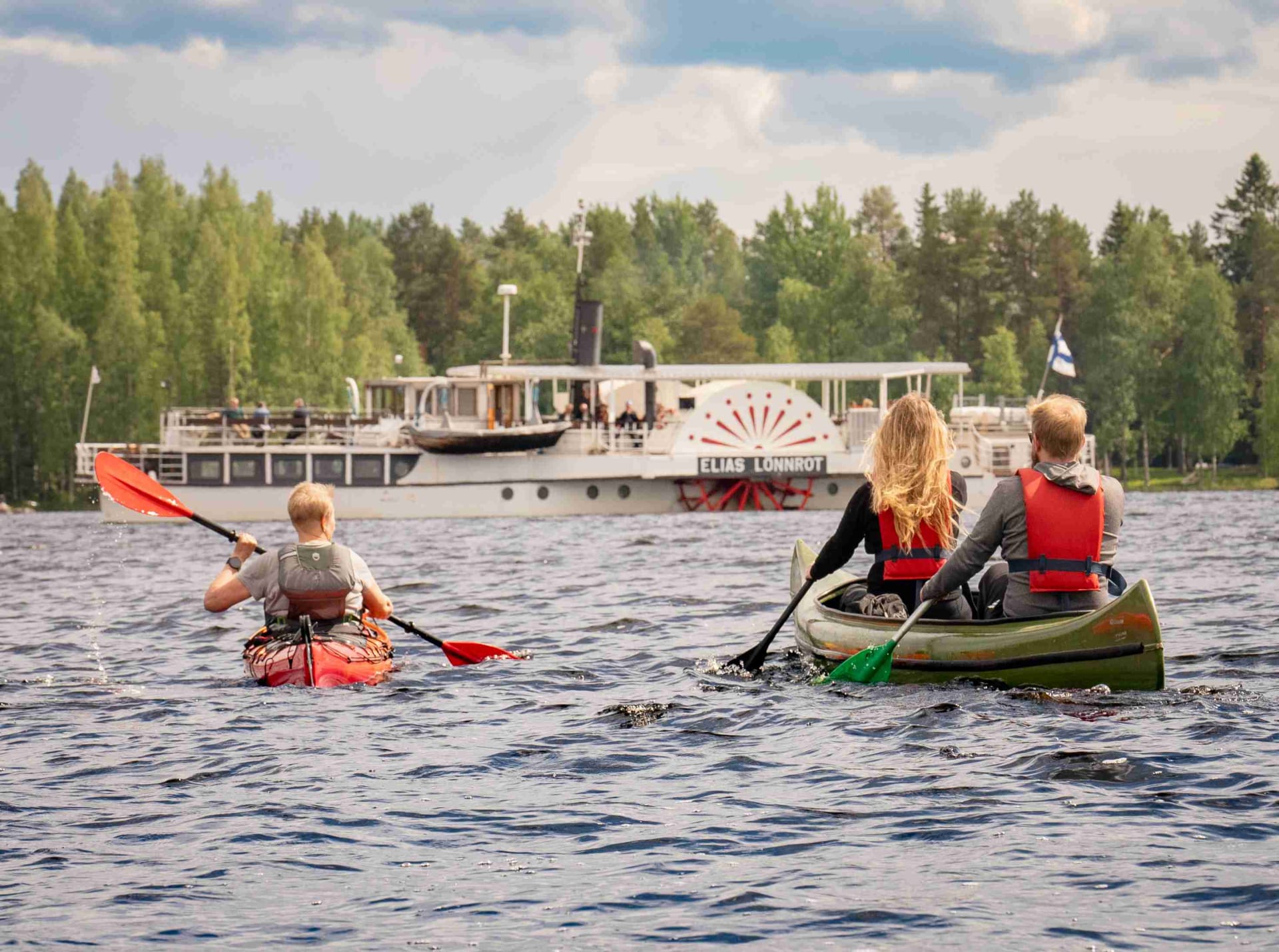Ihmiset melomassa järvellä kesällä.
