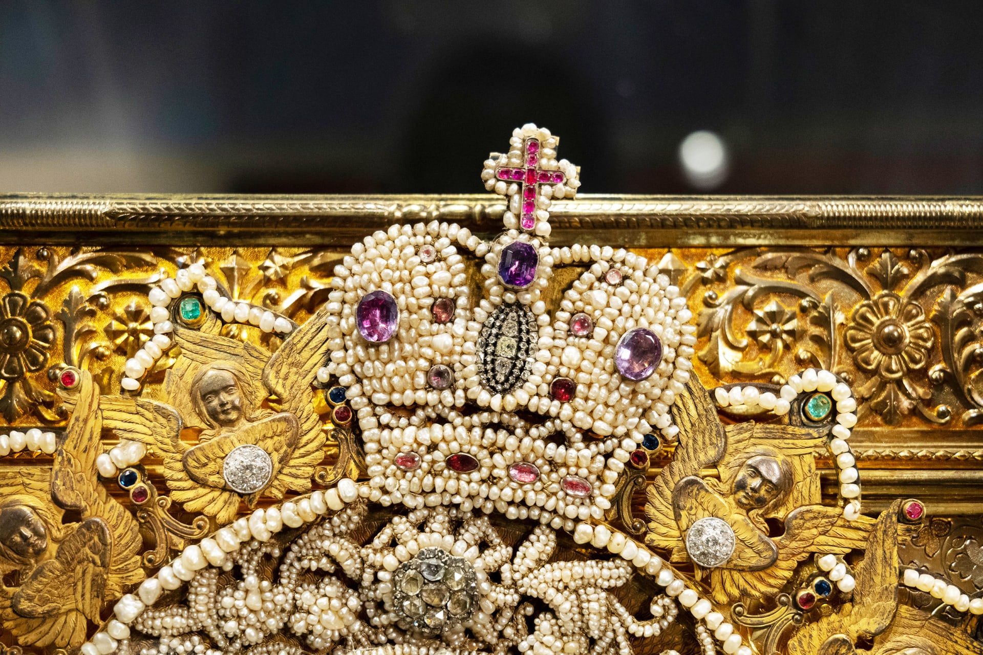 Yksityiskohta Jumalanäiti ikonin riisasta. Helmin ja jalokivin koristeltu kruunu jonka päällä risti. Detail from the riisa of the Mother of God icon. A crown decorated with pearls and gemstones, topped with a cross.