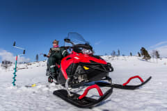 moottorikelkan päällä nainen pilkkikalastaa