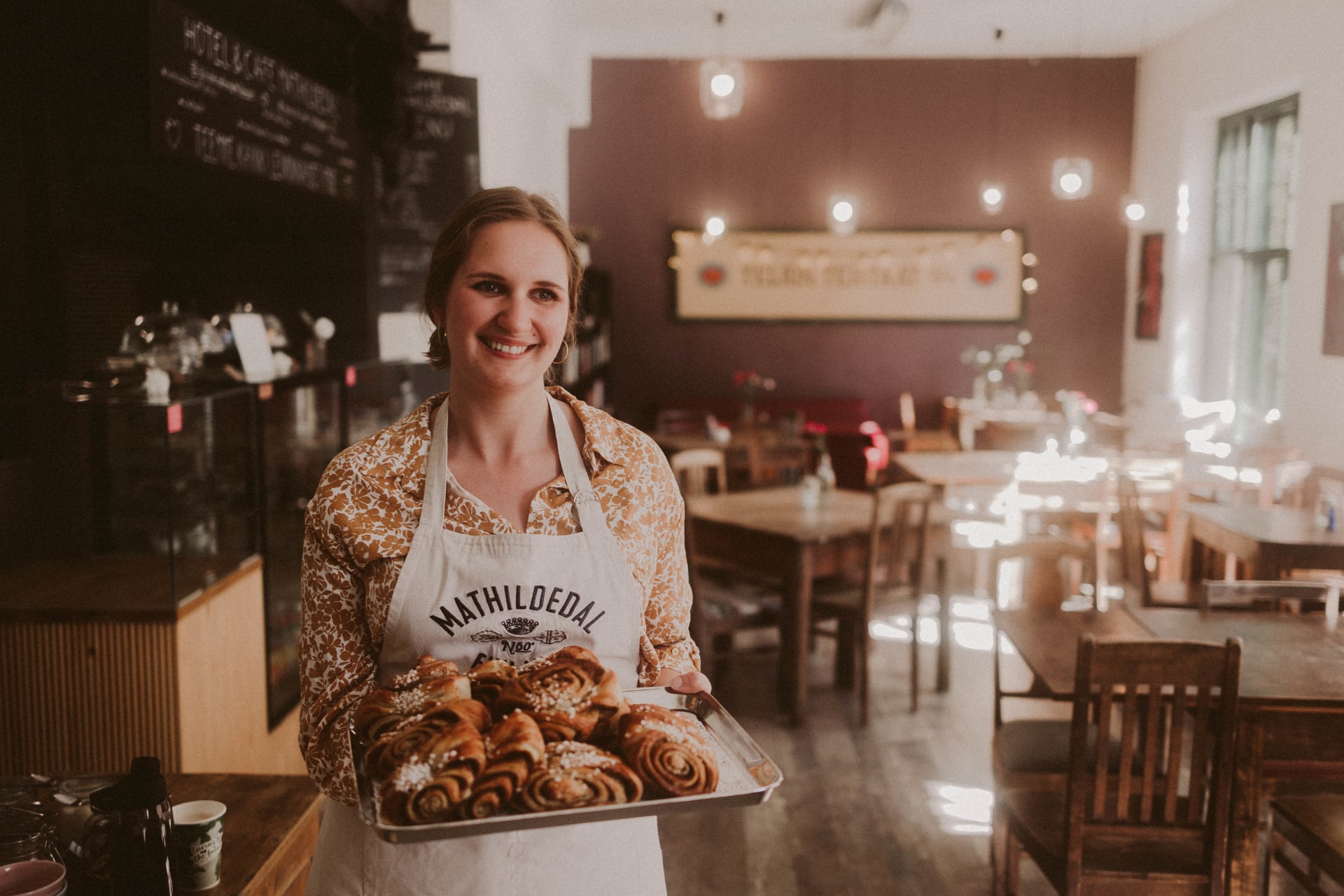 Baker with a tray of fresh cinnamon buns.