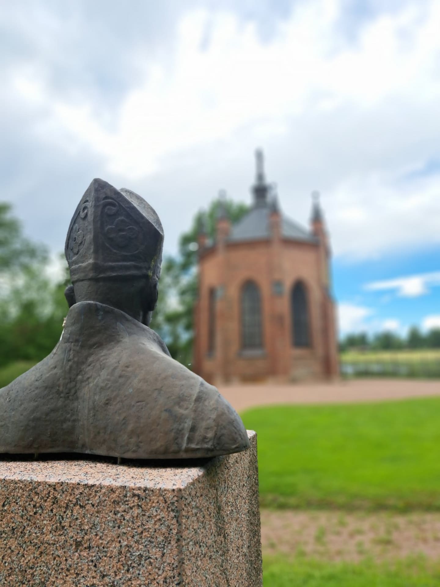 Torso patsas Pyhästä Henrikistä ja taustalla kappeli.