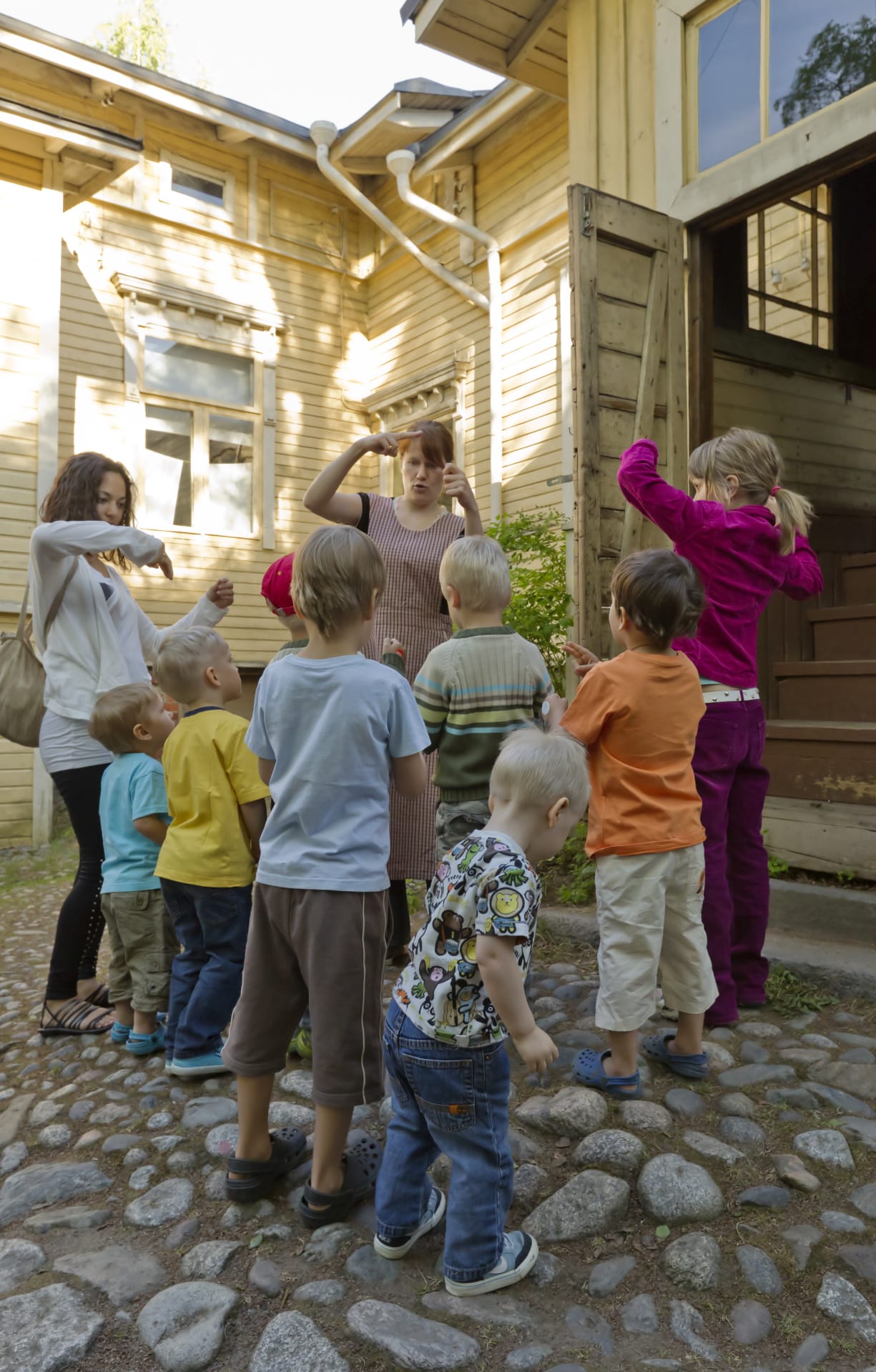 Lapset seisovat oppaan ympärillä Amurin pihalla.