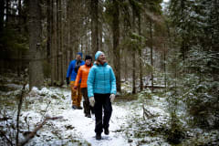 Kolme iloista retkeilijää kävelee jonossa lumisessa maisemassa. kuva. Maarit Vaahteranoksa.