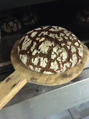 A bread shovel with baked bread on top.