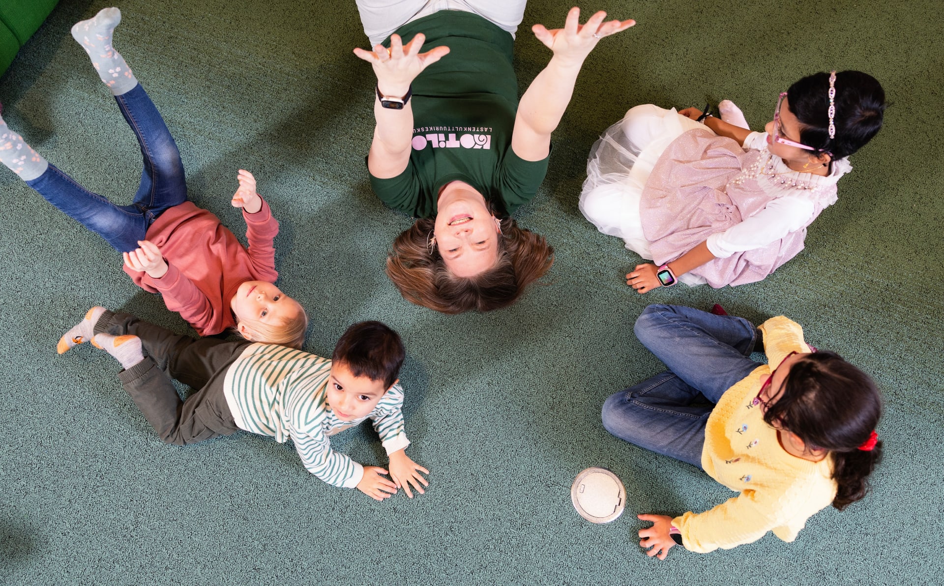 iloisia lapsia ja aikuinen leikkivät lattialla.
