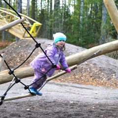A girl climbing up a climbing stand.