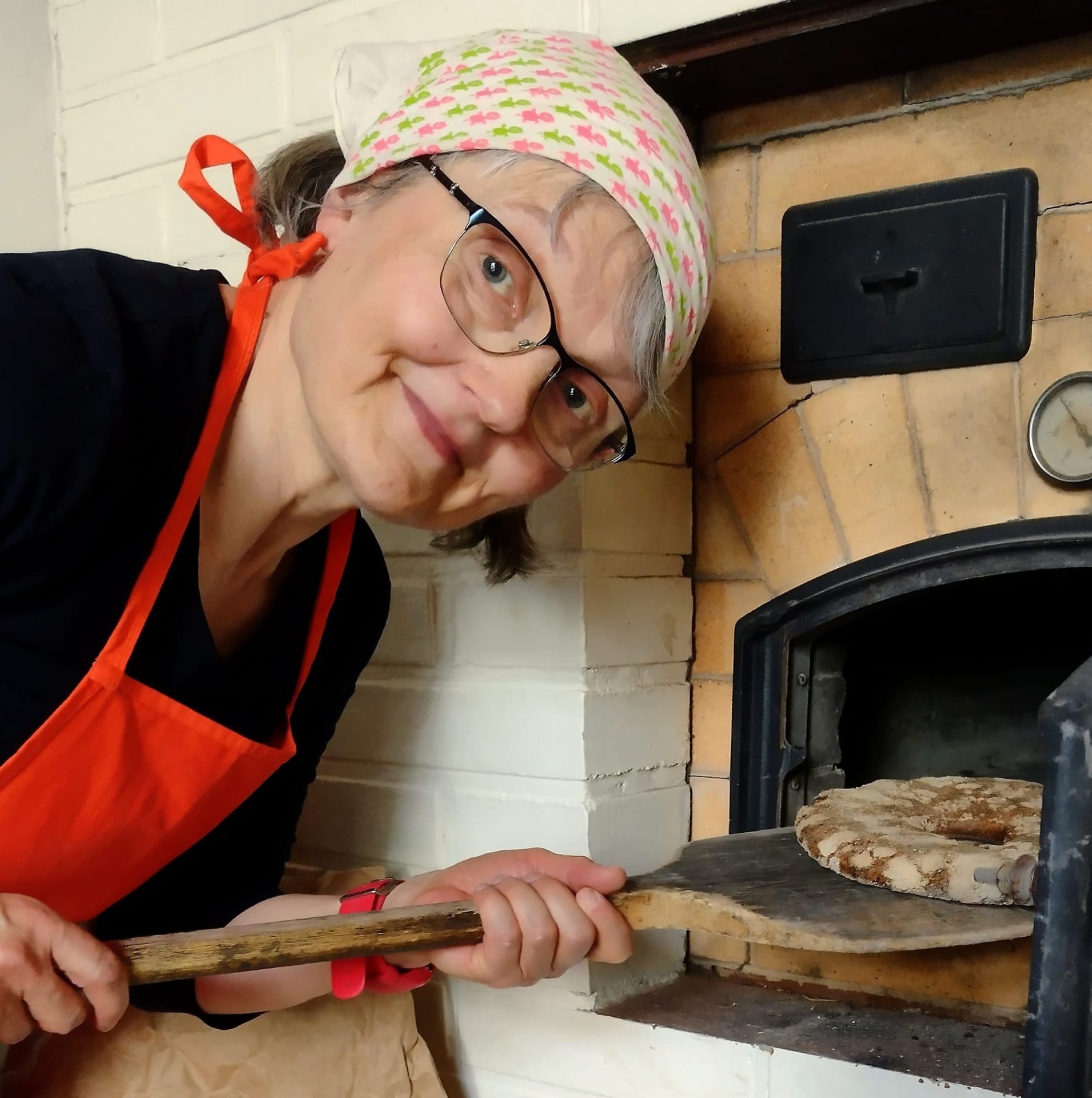 A person taking a freshly baked rye bread out of the oven.