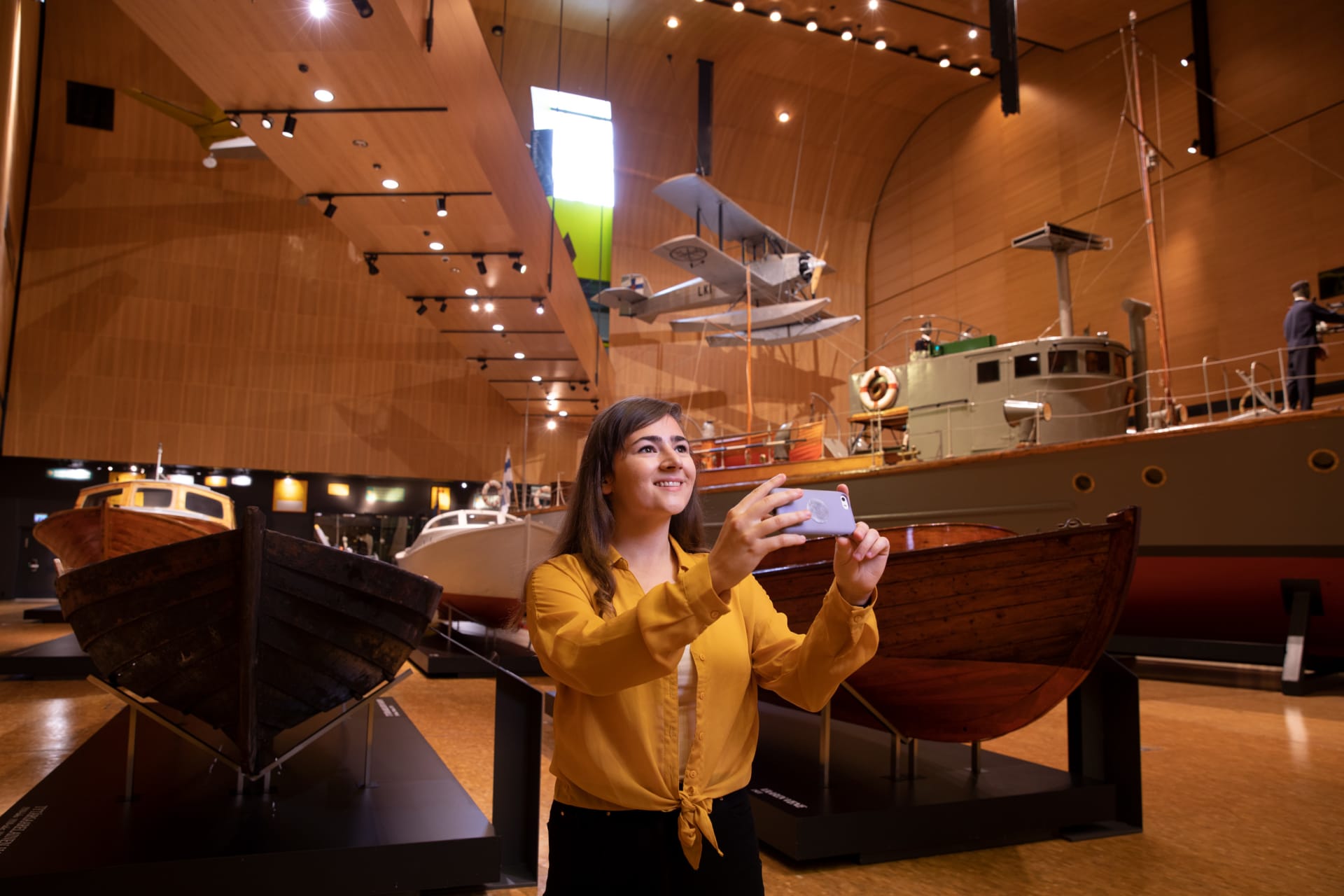 A lady taking a picture of boats inside the Boat hall. 