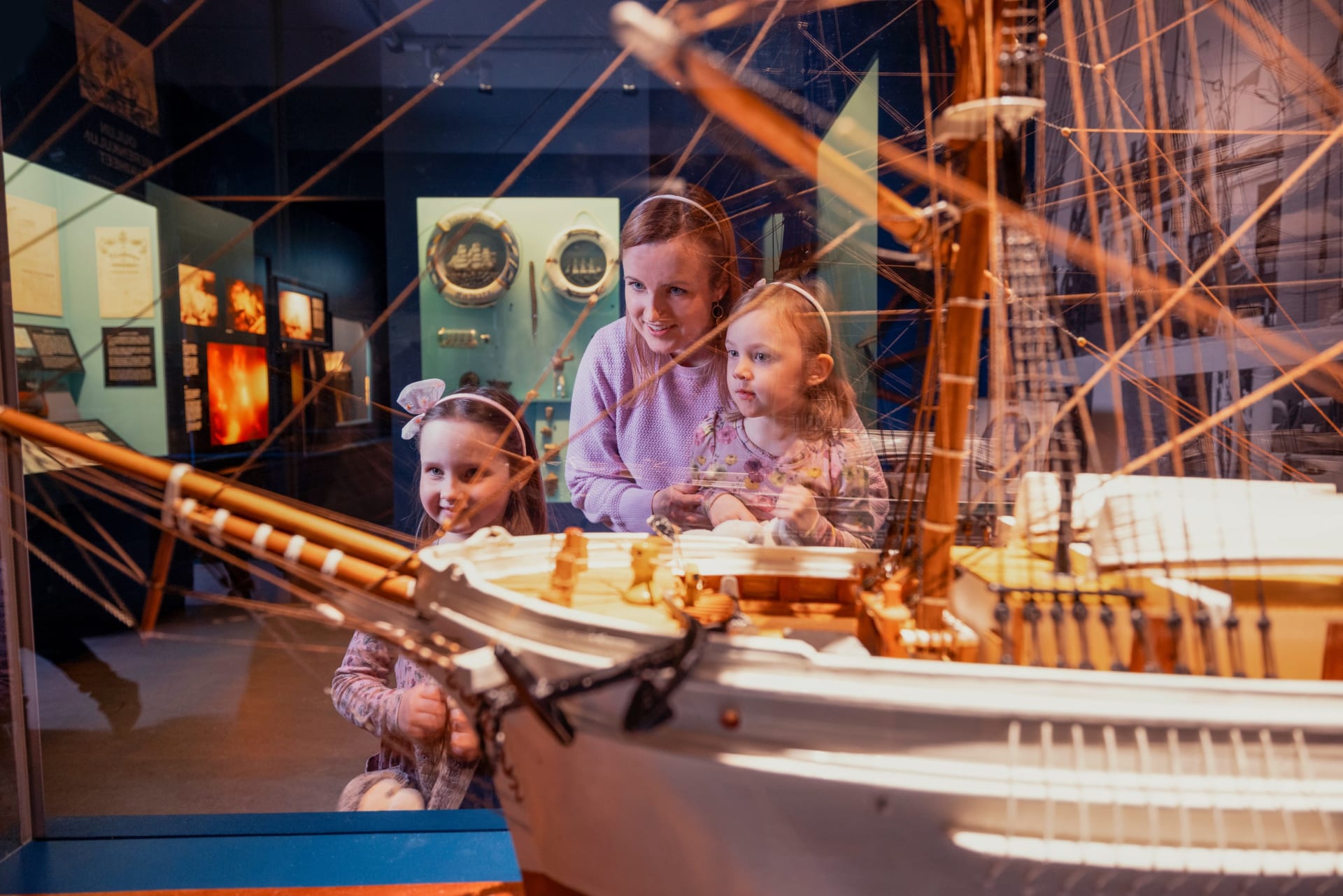 A family looking at the scale model of a sailing ship.